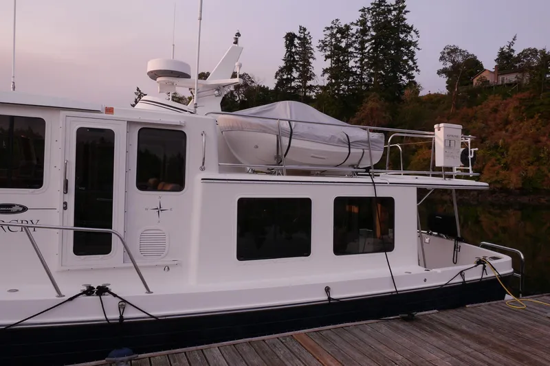 Slide: The Image of 2013 American Tug 395 docked, featuring a covered dinghy on the roof. - 11