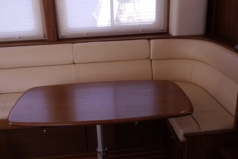 Slide: The Image of Cozy dining area in 2013 American Tug 395 with wooden table and beige seating. - 17