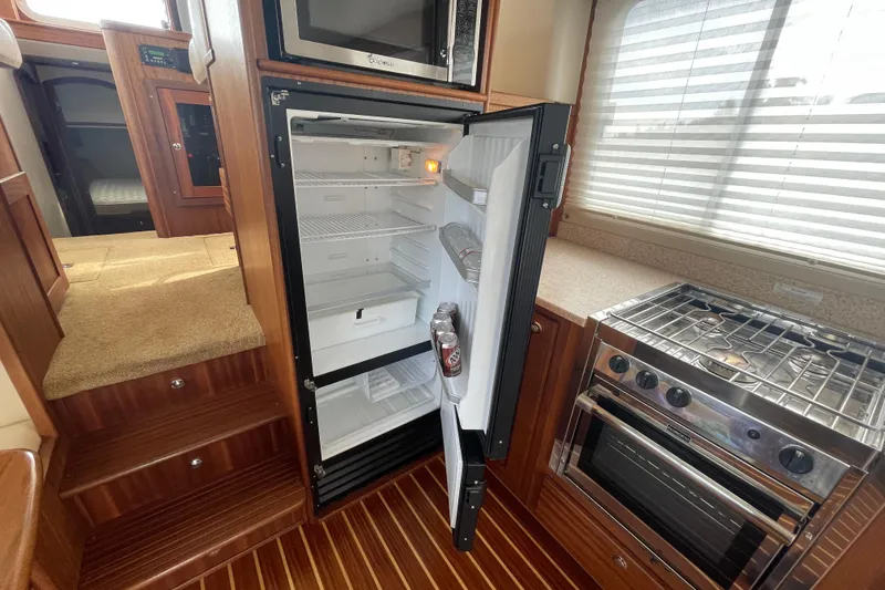 Slide: The Image of Interior of 2013 American Tug 395 showing kitchen with open fridge and stove. - 24