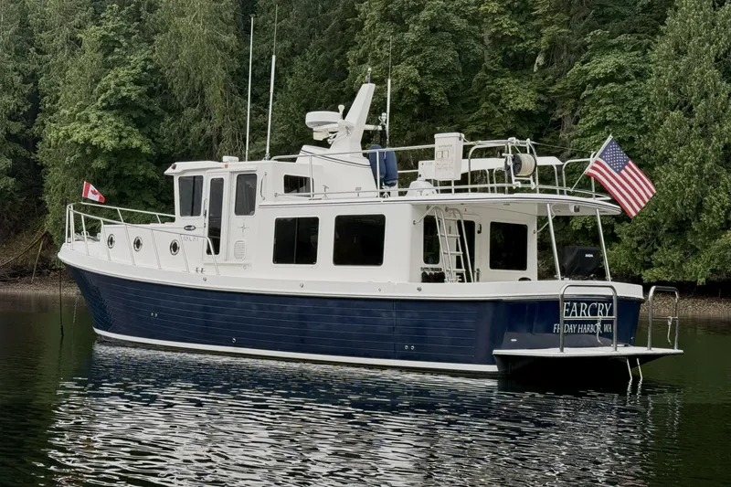 Slide: The Image of 2013 American Tug 395 boat on calm water, surrounded by lush green trees. - 3