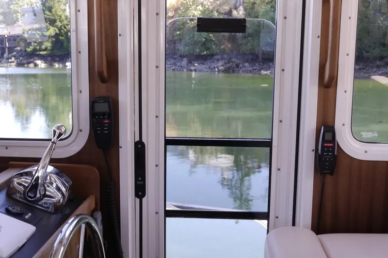 Slide: The Image of Interior view of 2013 American Tug 395, showcasing helm and serene waterway. - 37