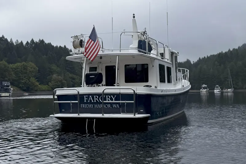 Slide: The Image of American Tug 395, 2013 model, moored in a serene harbor with forested backdrop. - 5