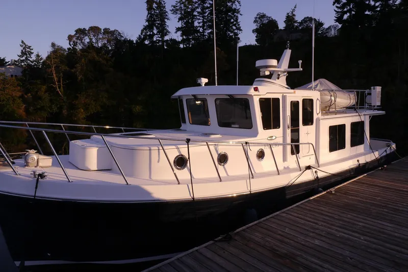 Slide: The Image of 2013 American Tug 395 docked, featuring a sleek white exterior and spacious deck. - 6