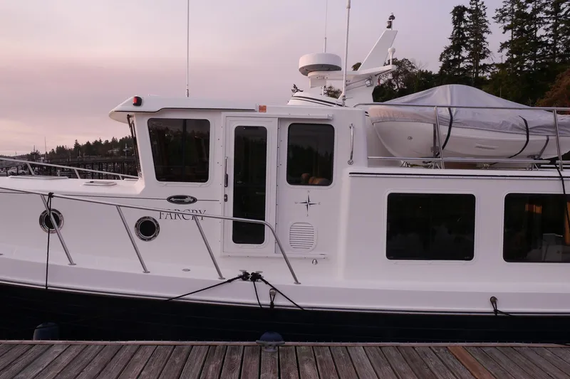 Slide: The Image of 2013 American Tug 395 docked, side view with covered dinghy on top. - 9
