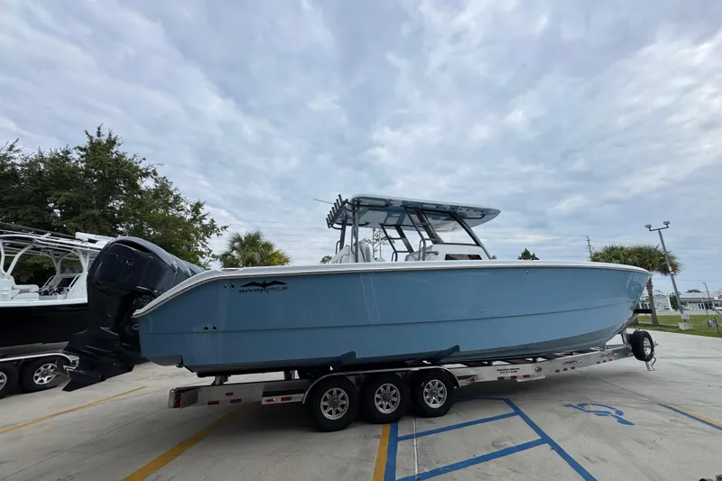 Slide: The Image of 2026 Invincible 38 Catamaran on trailer, blue hull, parked outdoors under cloudy sky. - 11