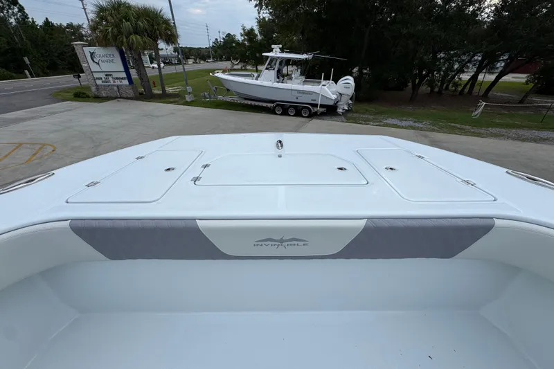 Slide: The Image of 2026 Invincible 38 Catamaran boat deck with storage compartments, parked near a marina. - 19