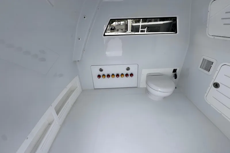 Slide: The Image of Interior of 2026 Invincible 38 Catamaran featuring a compact marine toilet and control panel. - 27