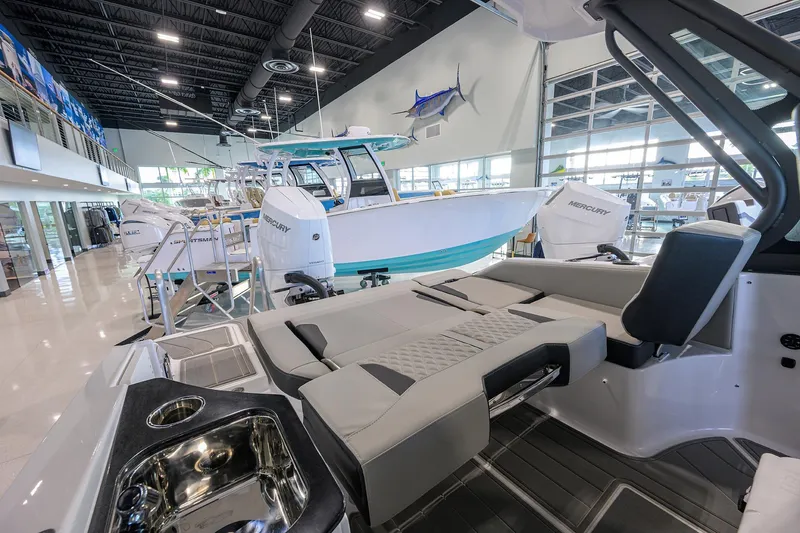 Slide: The Image of 2026 Monterey Elite 25 OB boat interior in a showroom with modern seating and amenities. - 29