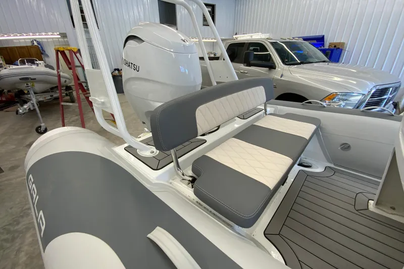Slide: The Image of Gala V500 boat interior with Tohatsu engine, featuring gray and white seating, in a garage setting. - 12
