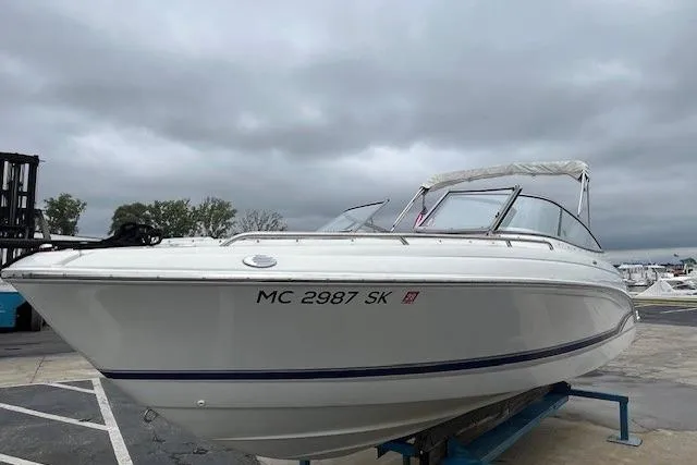 Slide: The Image of 2006 Formula 240 Bowrider boat on display, overcast sky, marina background. - 2