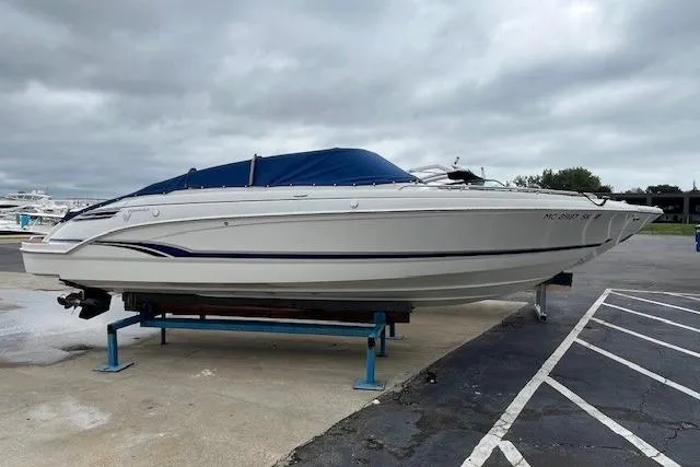 Slide: The Image of 2006 Formula 240 Bowrider boat on a stand, blue cover, overcast sky. - 25