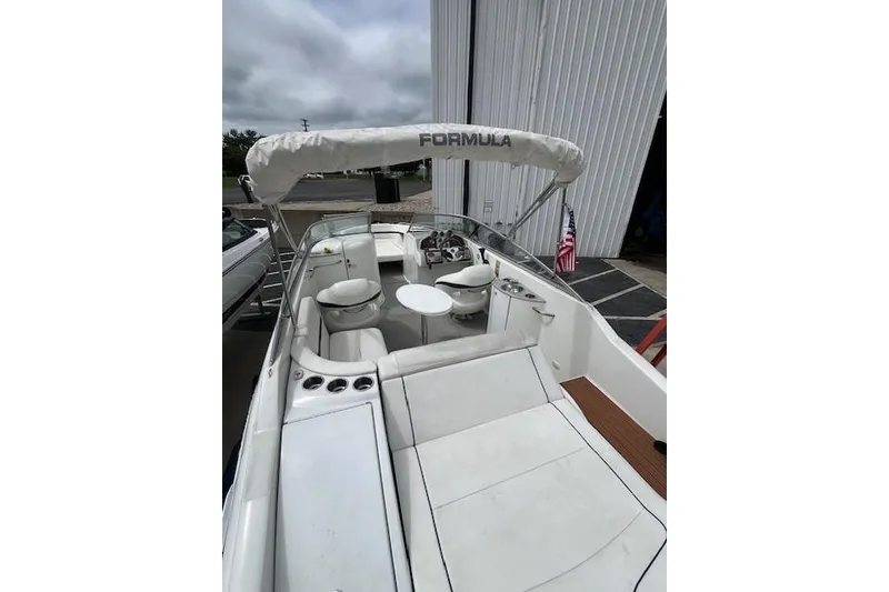 Slide: The Image of 2006 Formula 240 Bowrider boat with white seating and canopy, docked near a building. - 4