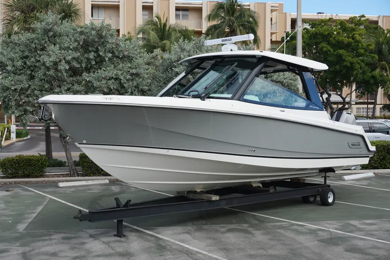 The Image of 2026 Boston Whaler 330 Vantage boat on trailer in parking lot, surrounded by trees. - 0