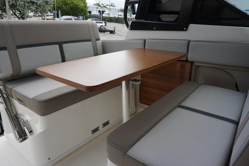 Slide: The Image of Interior seating area of 2026 Boston Whaler 330 Vantage with wooden table and cushioned seats. - 22