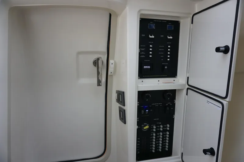 Slide: The Image of 2026 Boston Whaler 330 Vantage electrical panel with control switches and storage compartments. - 48
