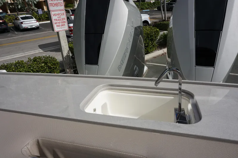 Slide: The Image of Boston Whaler 330 Vantage 2026 boat sink with faucet, parked Mercury engines in background. - 55