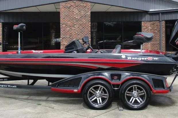 The Image of 2020 Ranger Z519 boat with red and black design on a trailer, parked outside a building. - 1