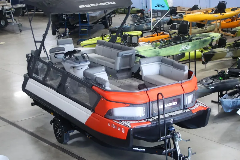 Slide: The Image of 2022 Sea Doo Switch pontoon boat in showroom with kayaks in background. - 3