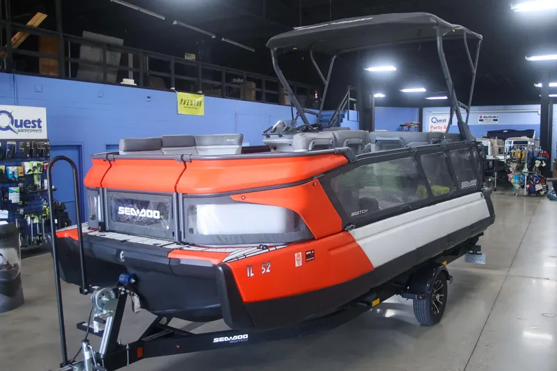 Slide: The Image of 2022 Sea Doo Switch pontoon boat displayed indoors, featuring vibrant orange and black design. - 5