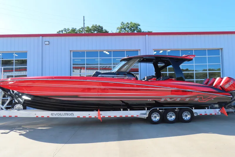 Slide: The Image of Red 2026 MTI 42 v powerboat on trailer, parked outside a modern building. - 1