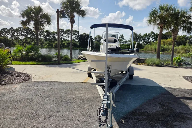 Slide: The Image of 2005 NauticStar 1800 Nautic Bay boat on trailer by scenic lake with palm trees. - 2