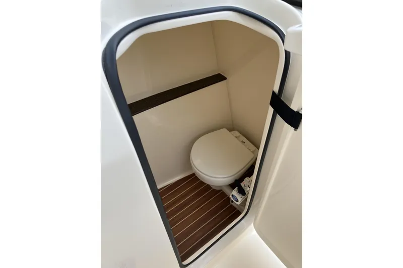 Slide: The Image of 2021 Scout 255 Dorado boat interior with compact marine toilet and wooden flooring. - 19