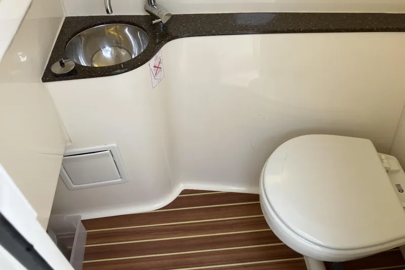 Slide: The Image of 2021 Scout 255 Dorado boat bathroom with sink and toilet, featuring wood-style flooring. - 20