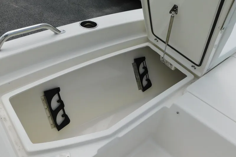 Slide: The Image of 2026 Pathfinder 2200 TRS boat storage compartment with open lid and rod holders. - 24