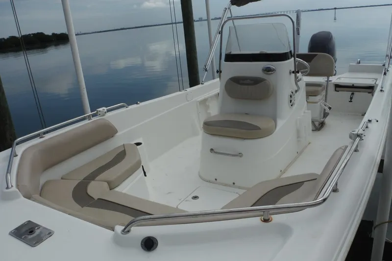 Slide: The Image of 2014 NauticStar 210 Angler boat interior with seating and steering console on calm water. - 12