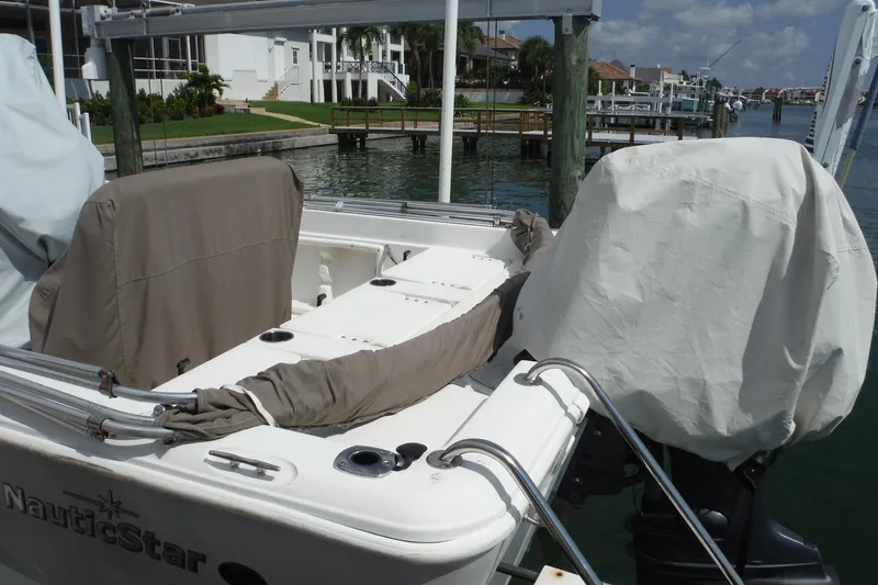 Slide: The Image of 2014 NauticStar 210 Angler boat docked, covered seats and motor, waterfront view. - 33
