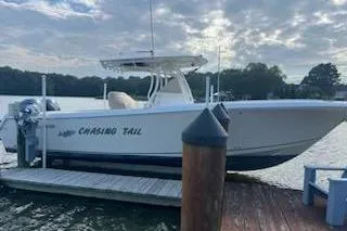 The Image of 2017 Sailfish 320 CC boat docked, named "Chasing Tail," under a cloudy sky. - 0