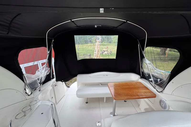 Slide: The Image of 2007 Sea Ray 280 Sundancer interior with seating and wooden table, enclosed by canopy. - 11