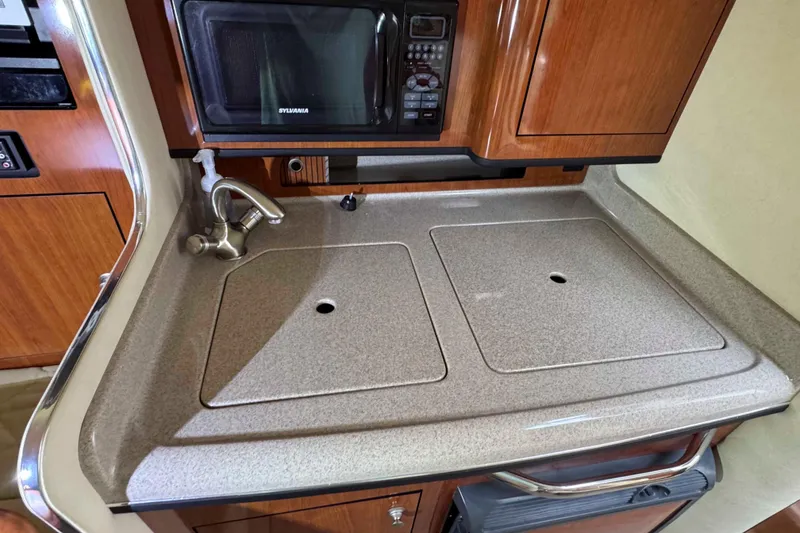 Slide: The Image of 2007 Sea Ray 280 Sundancer galley with sink, microwave, and wooden cabinetry. - 14