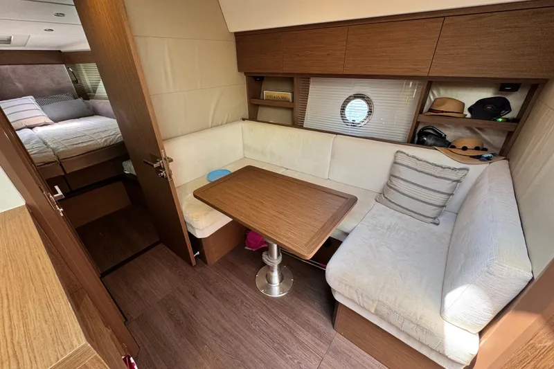 Slide: The Image of 2018 Beneteau Gran Turismo 46 interior with cozy seating, wooden table, and bedroom view. - 31