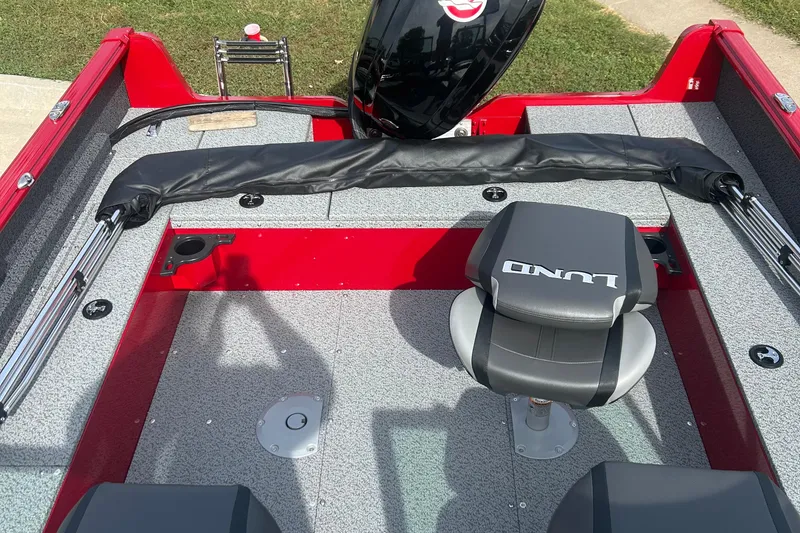 Slide: The Image of 2026 Lund 1800 Explorer Sport boat interior with seating and motor, featuring red and gray design. - 2