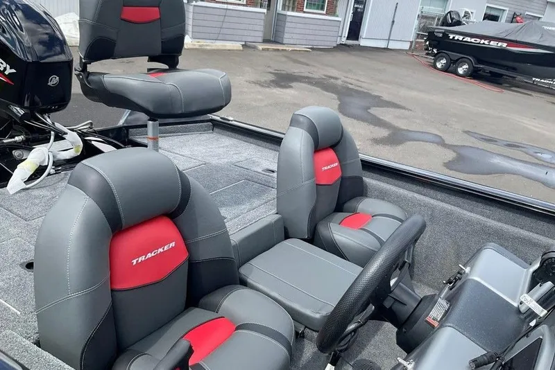 Slide: The Image of 2025 Tracker Pro Team 175 boat interior with gray and red seating, steering wheel, and motor. - 13