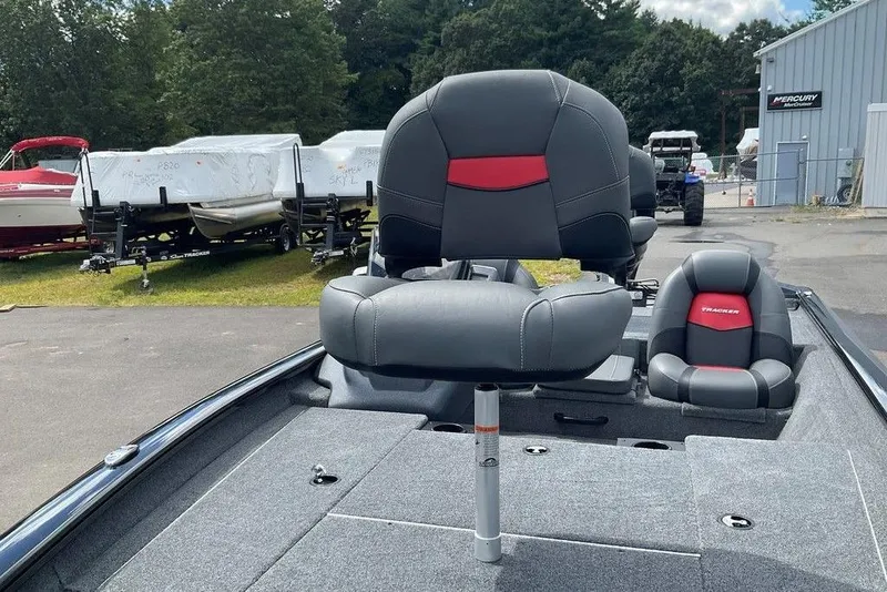 Slide: The Image of 2025 Tracker Pro Team 175 boat with gray and red seating, parked outdoors. - 16