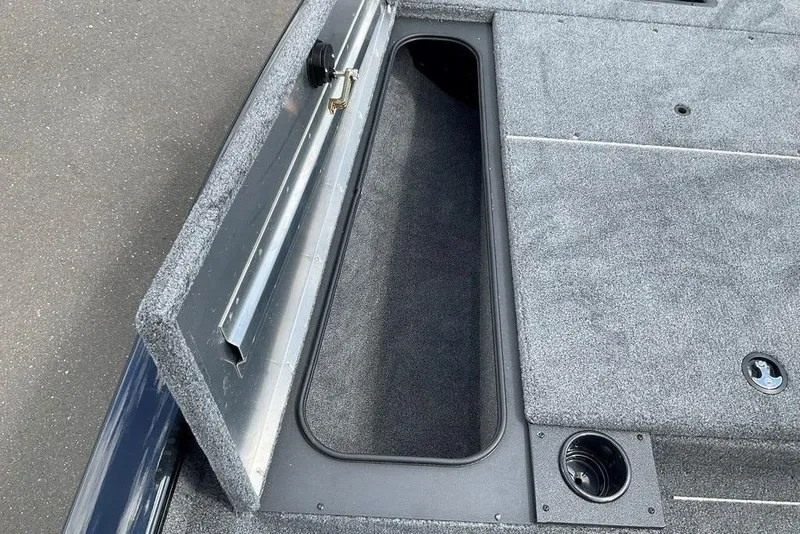Slide: The Image of 2025 Tracker Pro Team 175 boat storage compartment with gray carpeted interior. - 25