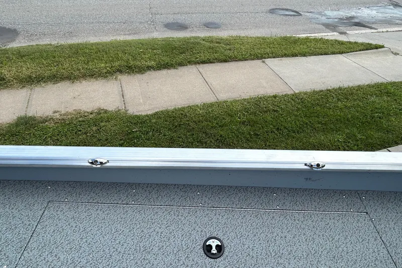 Slide: The Image of 2026 Lund 2075 Alaskan Sport boat detail with sidewalk and grass in background. - 13