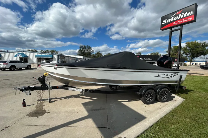 Slide: The Image of 2026 Lund 2075 Alaskan Sport boat on trailer, parked near Safelite AutoGlass. - 2