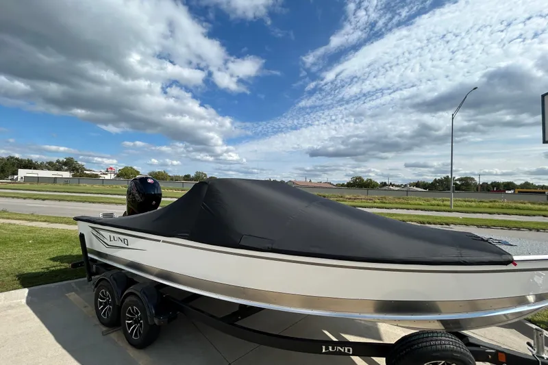 Slide: The Image of 2026 Lund 2075 Alaskan Sport boat with cover on trailer, under a partly cloudy sky. - 7