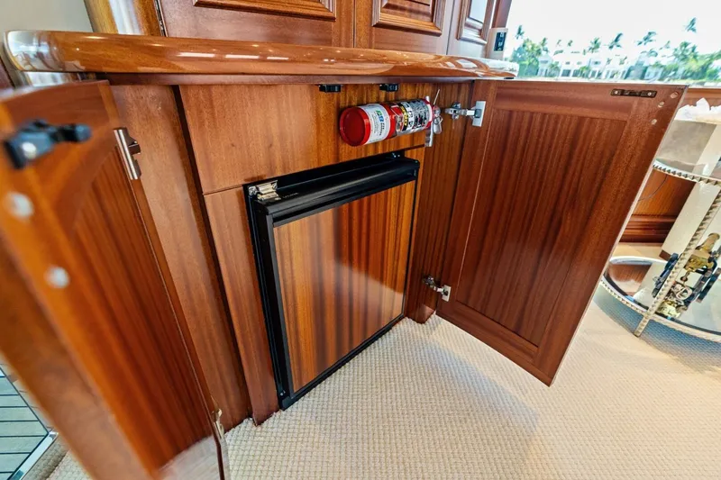 Slide: The Image of Wooden cabinet with open doors, revealing a mini fridge and fire extinguisher on a Westport 2011 yacht. - 42