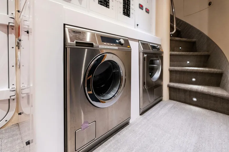 Slide: The Image of Laundry area with Miele appliances on a 2011 Westport yacht, near carpeted stairs. - 75
