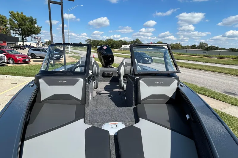 Slide: The Image of 2026 Lund 1875 Crossover XS boat with open cockpit, parked outdoors under blue sky. - 14