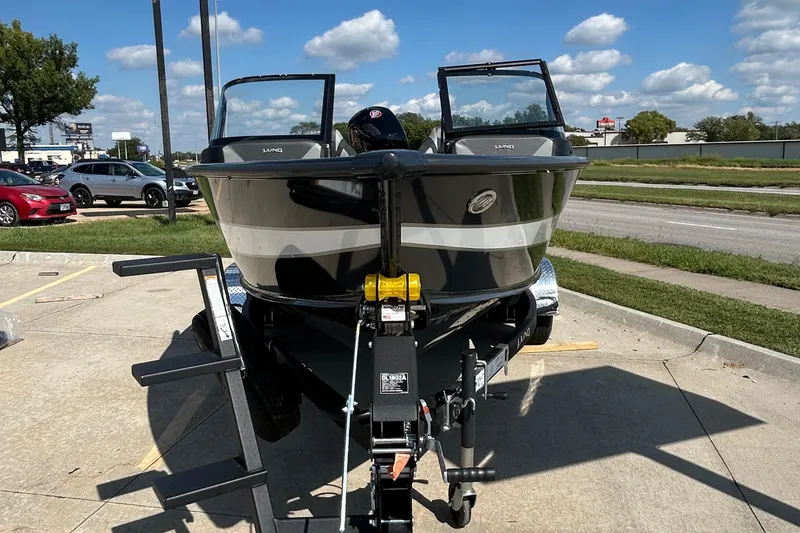 Slide: The Image of 2026 Lund 1875 Crossover XS boat on trailer, parked outdoors under a clear sky. - 15