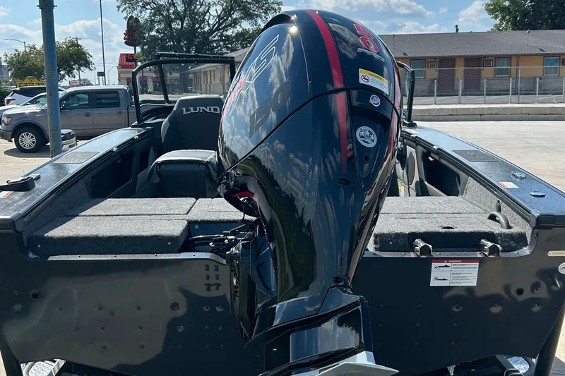 Slide: The Image of 2026 Lund 1875 Crossover XS boat with powerful outboard motor in a parking lot. - 17