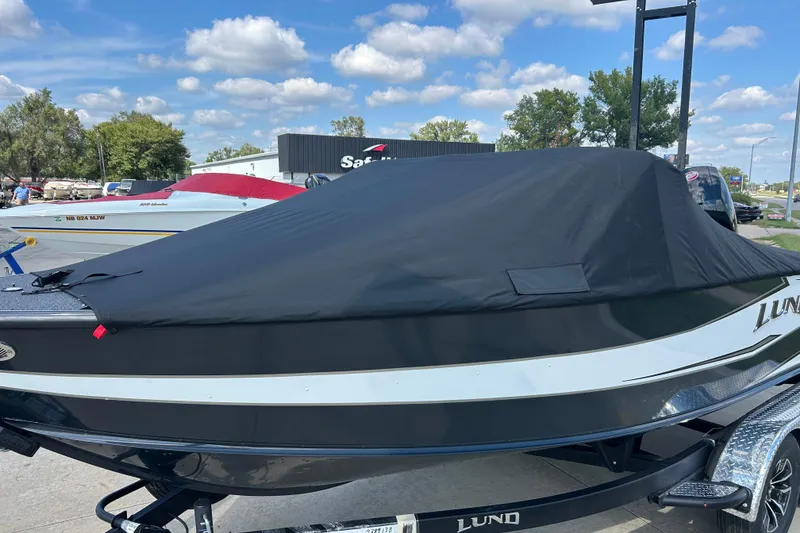 Slide: The Image of 2026 Lund 1875 Crossover XS boat with black cover, parked outdoors. - 4