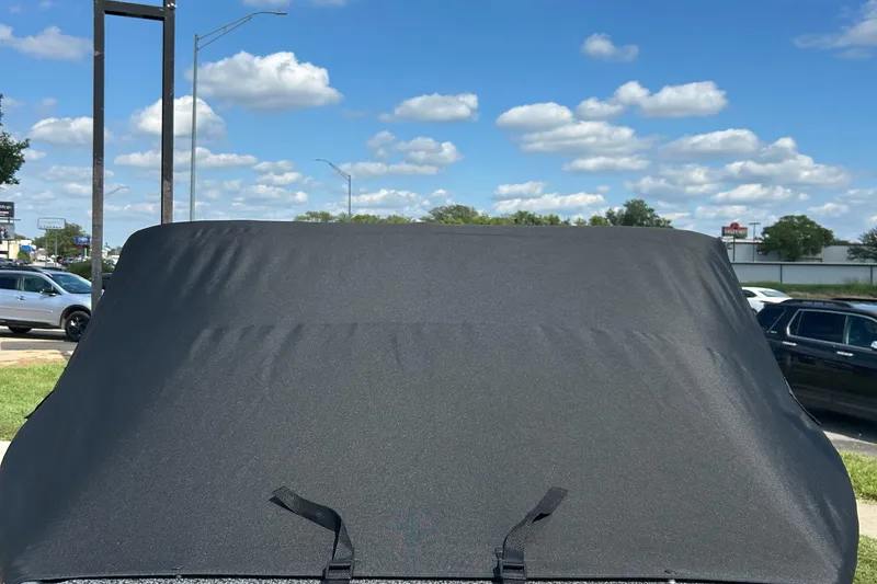 Slide: The Image of 2026 Lund 1875 Crossover XS boat with black cover under a clear blue sky. - 6