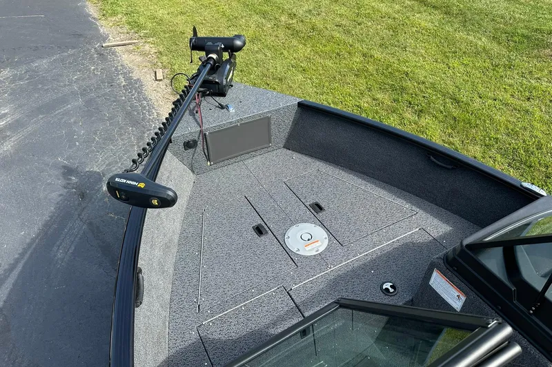 Slide: The Image of 2026 Lund 1650 Rebel XL Sport boat deck with trolling motor, parked on grass. - 10