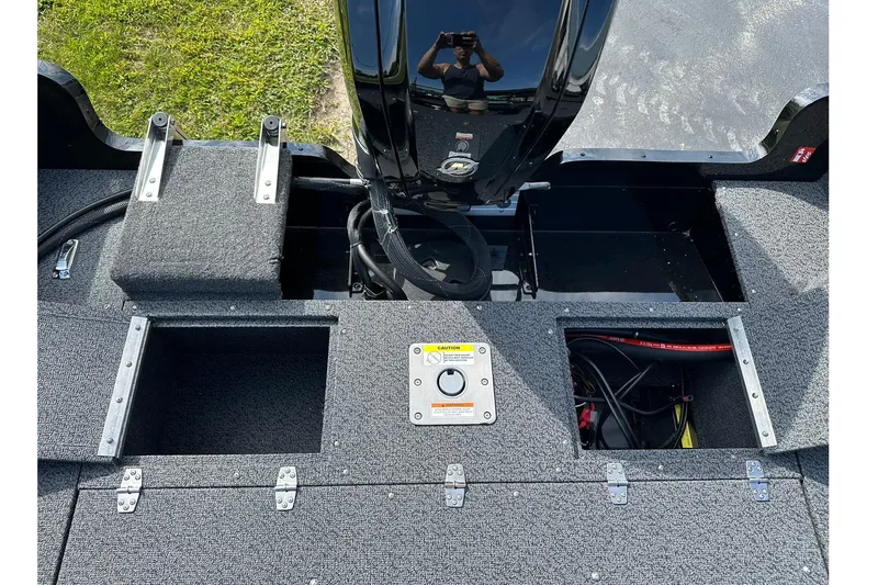 Slide: The Image of 2026 Lund 1650 Rebel XL Sport boat interior with storage compartments and motor. - 15